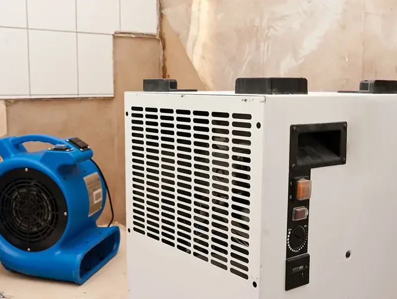 Air mover and dehumidifier drying a room after the lower drywall was cut away
