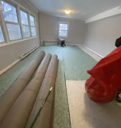 Waterlogged carpet pulled back and rolled for extraction in a flooded room
