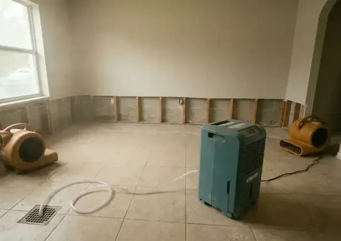 Dehumidifier and air movers drying a room after the baseboards came off