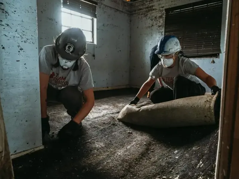 Crew rolling up soaked carpet, a Pasadena flood risk
