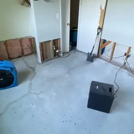 Two air movers and a dehumidifier set up in a wet living room