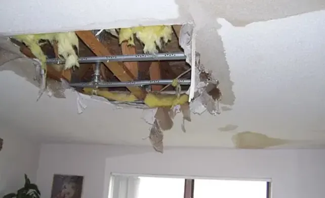 Ceiling drywall and insulation torn open after a leak from above
